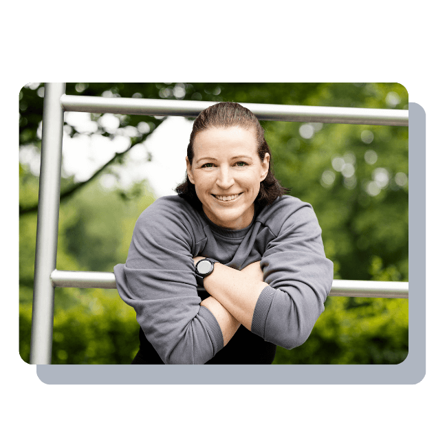 Ein Foto der Fitnesstrainerin Hanna Winter, die sich mit dem Oberkörper lächelnd auf ein Gerüst stützt.