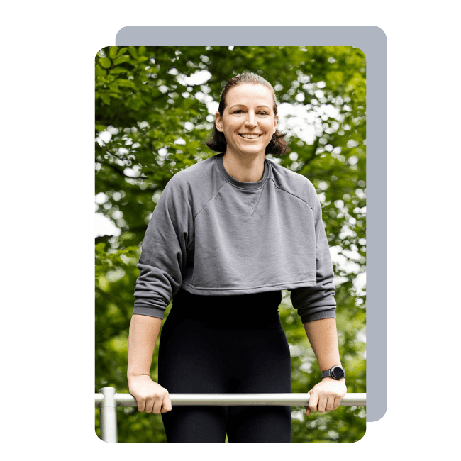 Ein Foto der Fitnesstrainerin Hanna Winter, die sich lachend mit den Armen auf einem Gerüst abstützt.